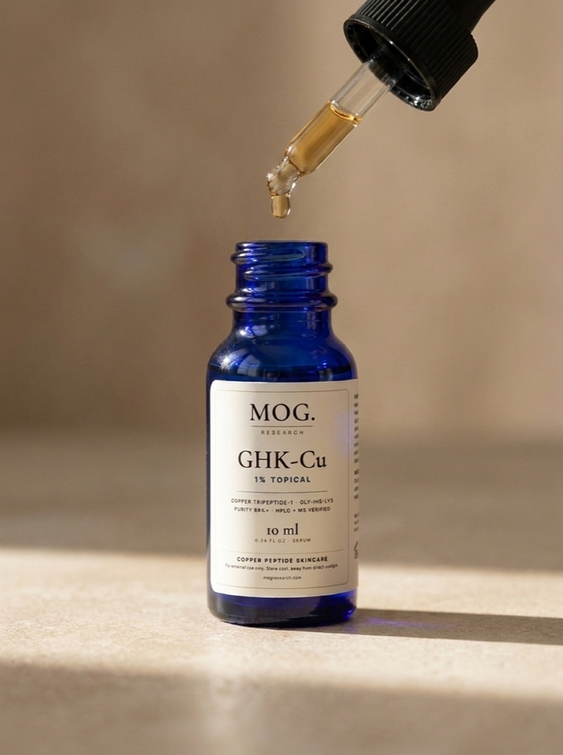 A single blue drop of MOG Glow Peptide Serum hanging from the glass dropper